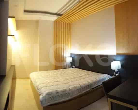 A well-lit bedroom with a large bed, wooden paneling, and a desk.
