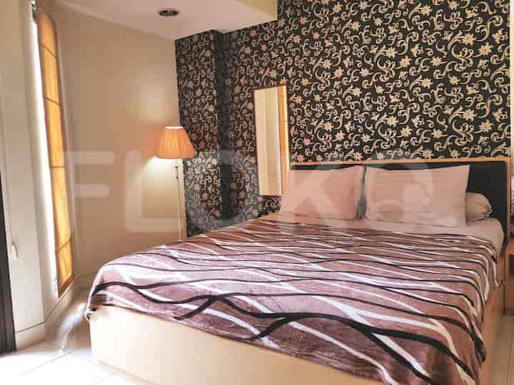 Bedroom with a patterned blanket on the bed and a floor lamp.