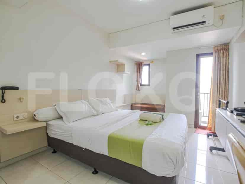 Bedroom featuring a double bed with white linens, a kitchen and balcony.