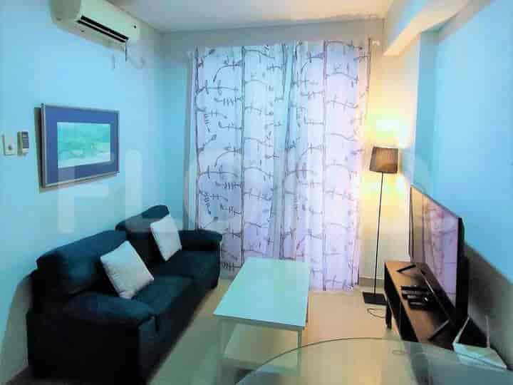 A living room with a navy blue sofa, wall-mounted TV, and sheer curtains.