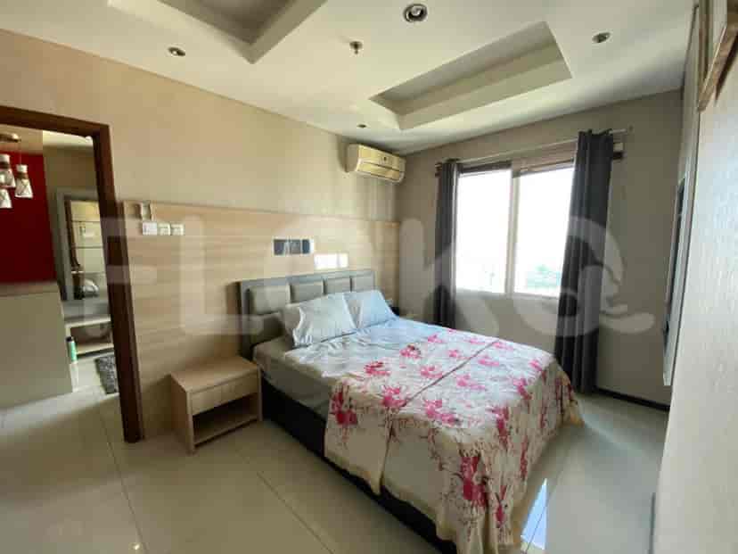 A well-lit bedroom with a double bed, nightstand, and large window.