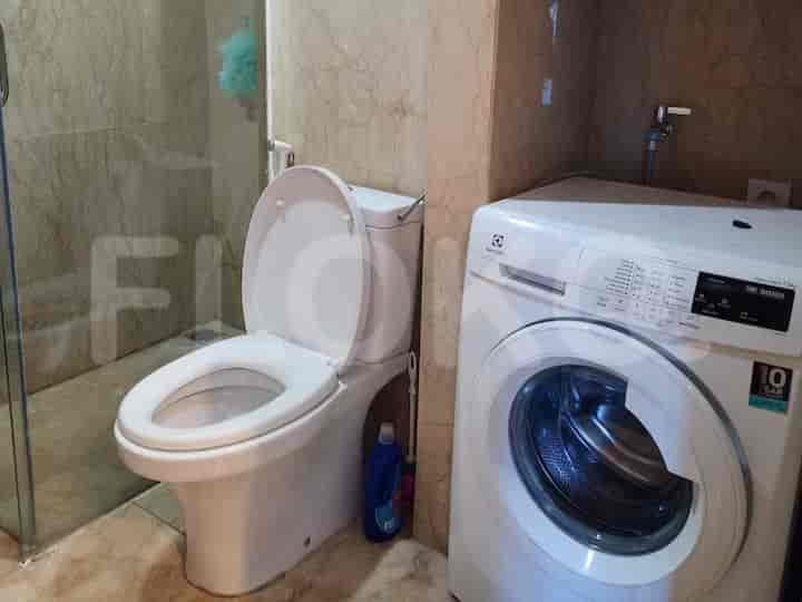 A bathroom with a toilet, washing machine, and shower area.