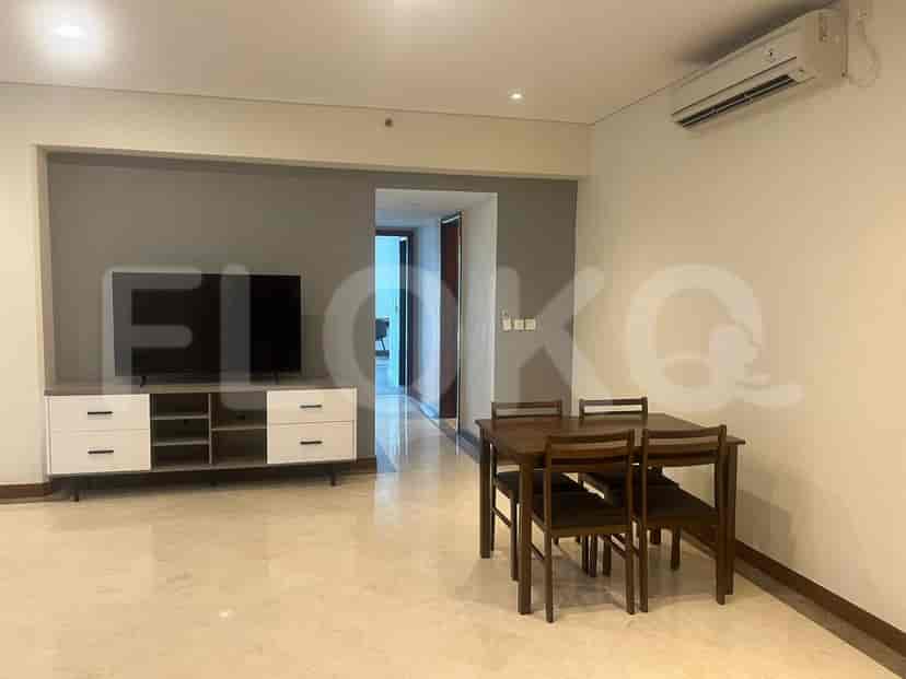 A modern living and dining area featuring a dining table, TV console, and neutral-toned walls.