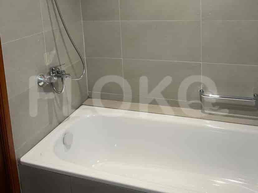 A modern bathroom with a bathtub, faucet, and grey tiles.
