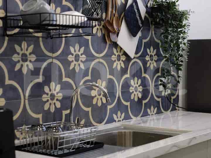 A stylish kitchen with patterned tiles, sink, and utensils.