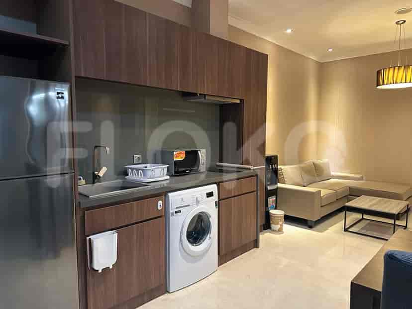Modern kitchenette with built-in appliances, next to a grey sofa.