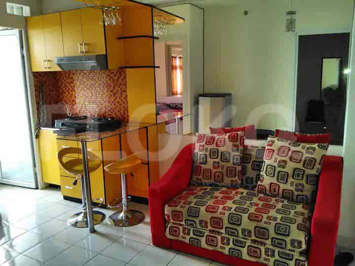 A modern kitchen with yellow cabinets, a glass breakfast bar, and a red and brown tiled backsplash.