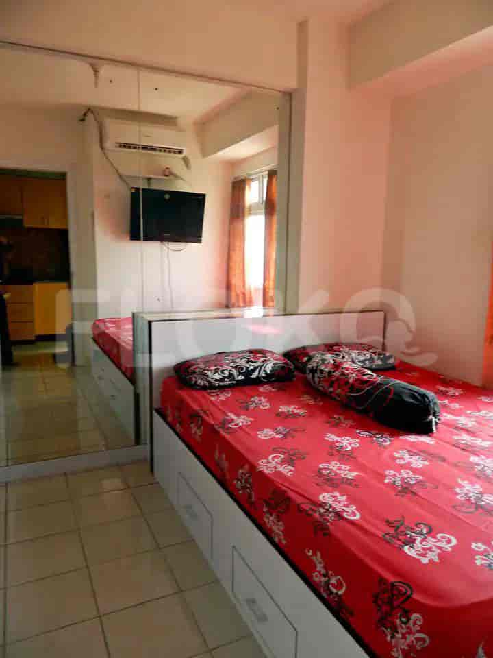 A well-lit bedroom with a bed and television.