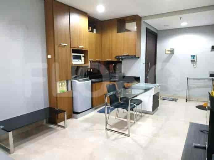 A compact kitchen with wooden cabinets, a small dining table, and kitchen appliances.