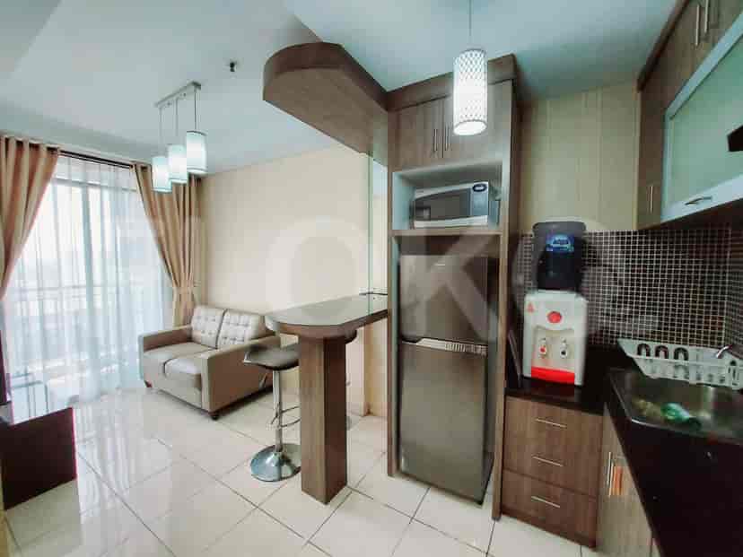 Compact kitchen area with refrigerator, microwave, and seating area.