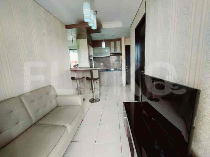 A modern living space with a grey sofa, bar seating, and a kitchenette with appliances.