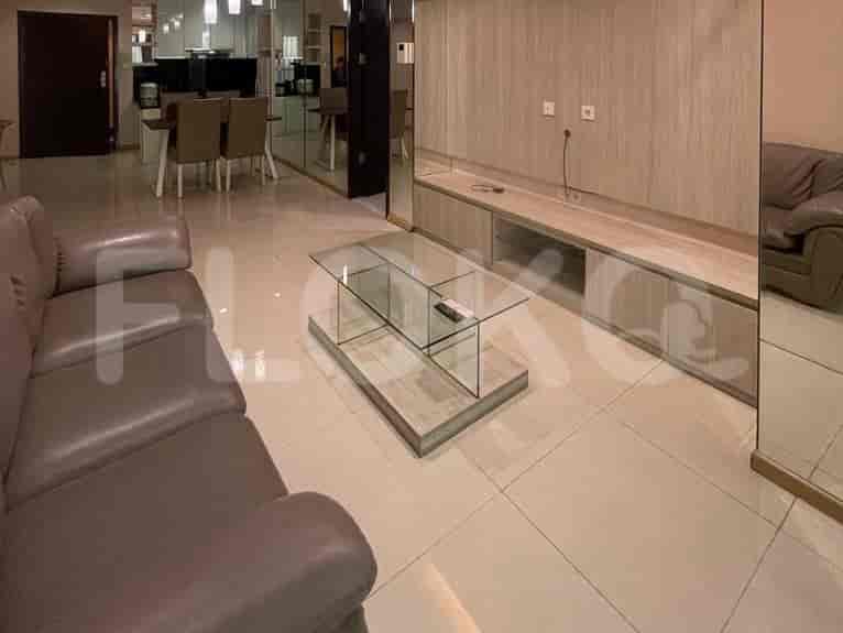 A modern living room with a grey sofa, glass coffee table, and a large window with a view.