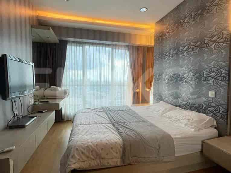 A bedroom with a large bed, curtains, and a TV.
