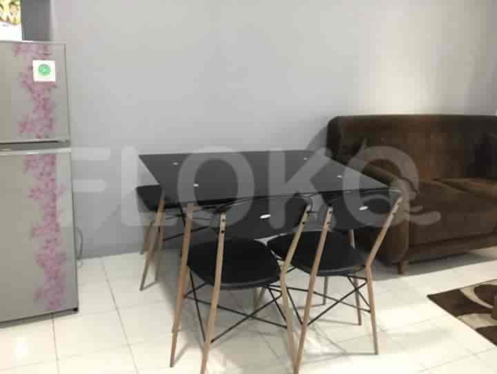 A dining area with a black table, chairs, and refrigerator.