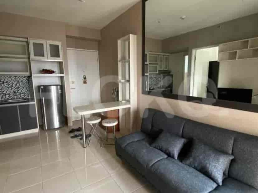 A cozy living area with a grey sofa, a small kitchen table with stools, and a kitchen partially visible.