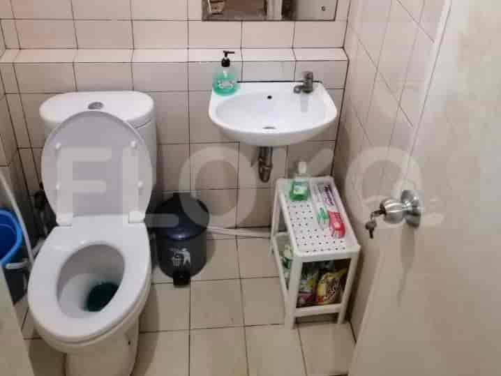A small bathroom with a toilet, sink, and shelf.