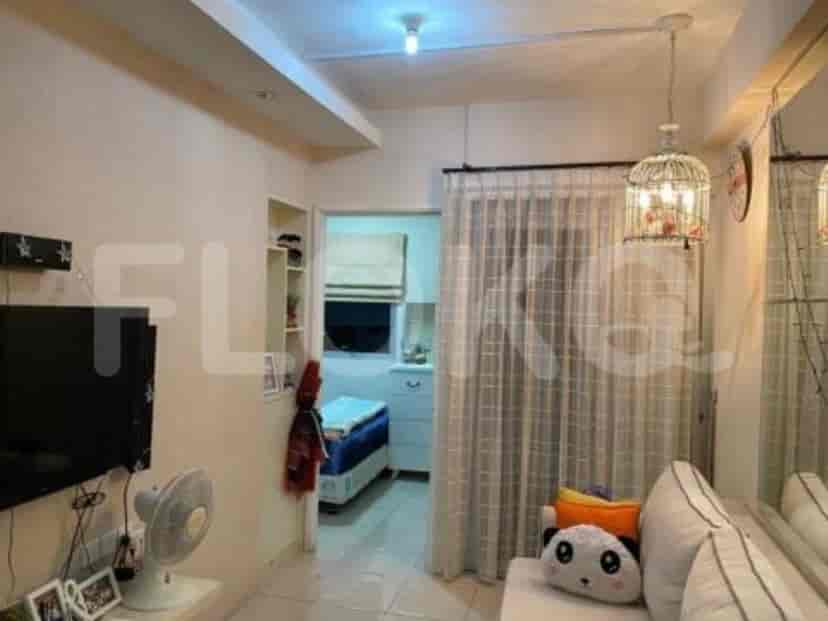 A cozy living space featuring a sofa, a mounted TV, and a small fan.