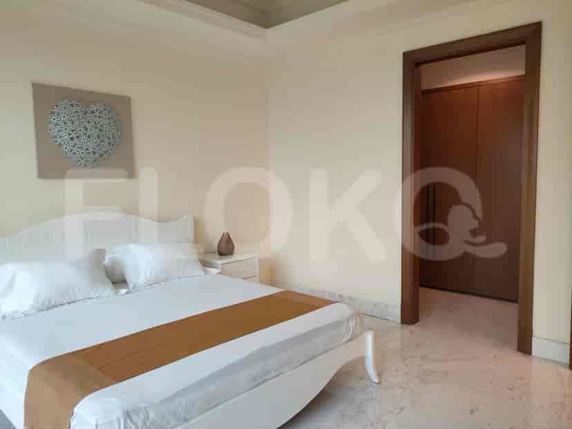 A bedroom with a white bed, nightstand, and artwork.