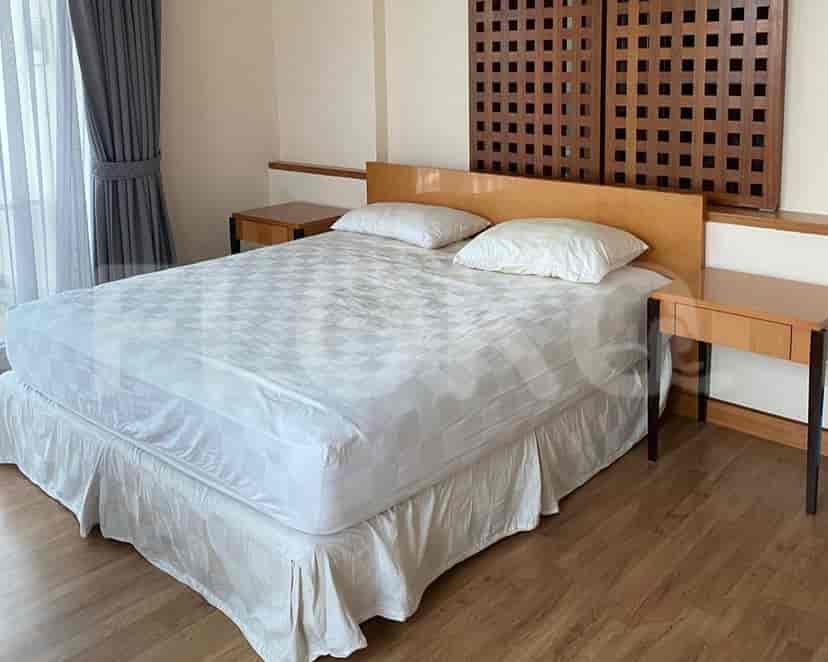A bedroom featuring a large bed, nightstands, and wooden wall panels.