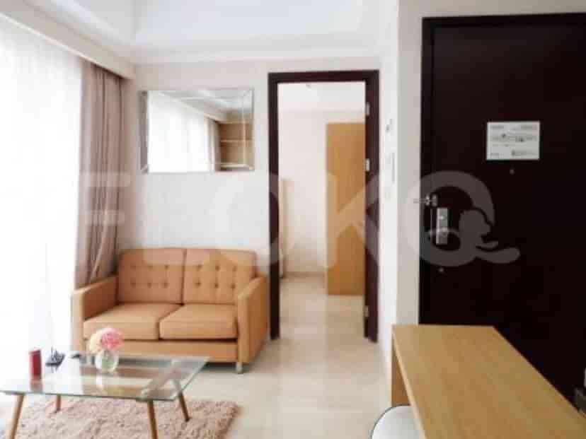 Ruang tamu menampilkan sofa nyaman dengan meja kopi dan pemandangan ruangan di sebelahnya.