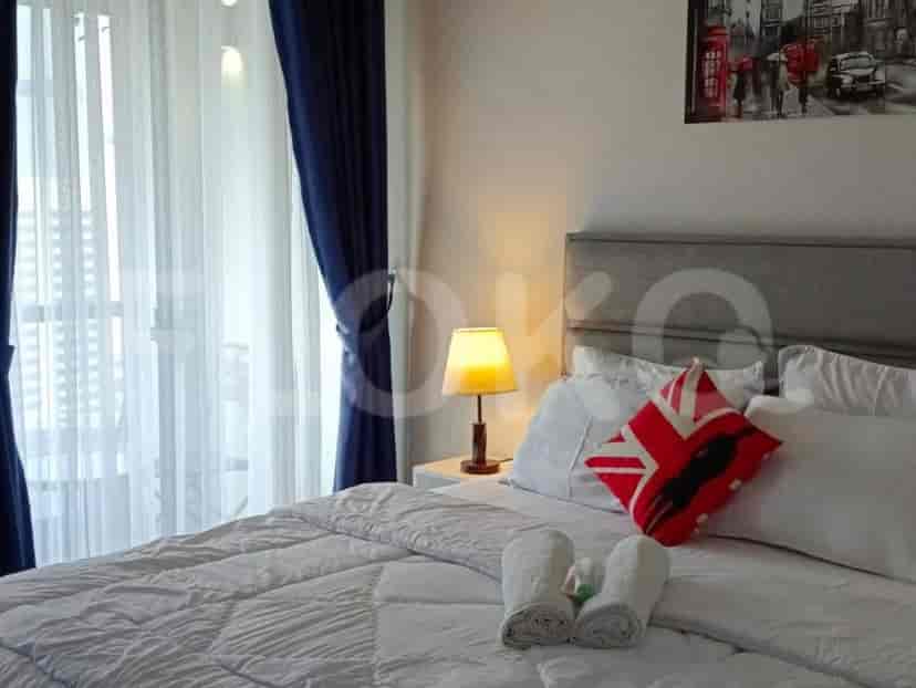 A bright bedroom with a bed, lamp, and curtains.