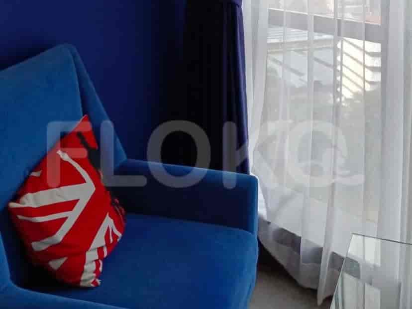 A lounge area with a blue chair and curtains.