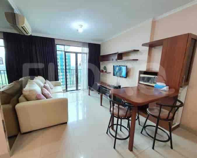 Living room with a cream sofa, dining area, and balcony.