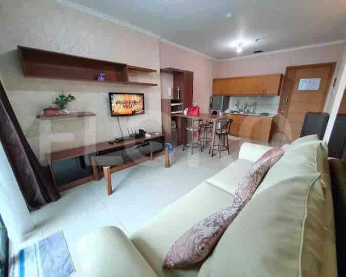 Open-plan living room with kitchen, sofa, and TV.