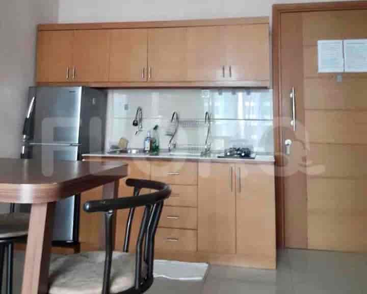 The kitchen features wooden cabinets, a refrigerator, and a dining table.