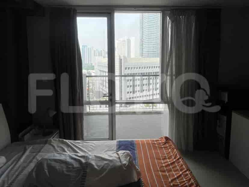 Bedroom with a view of the city through large windows.