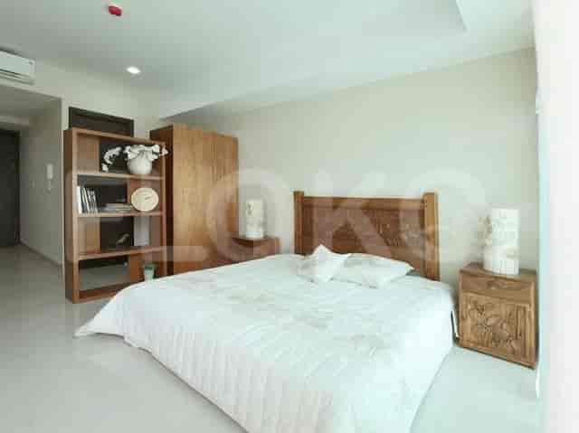 A well-lit bedroom featuring a large bed, wooden furniture, and a bright, minimalist aesthetic.