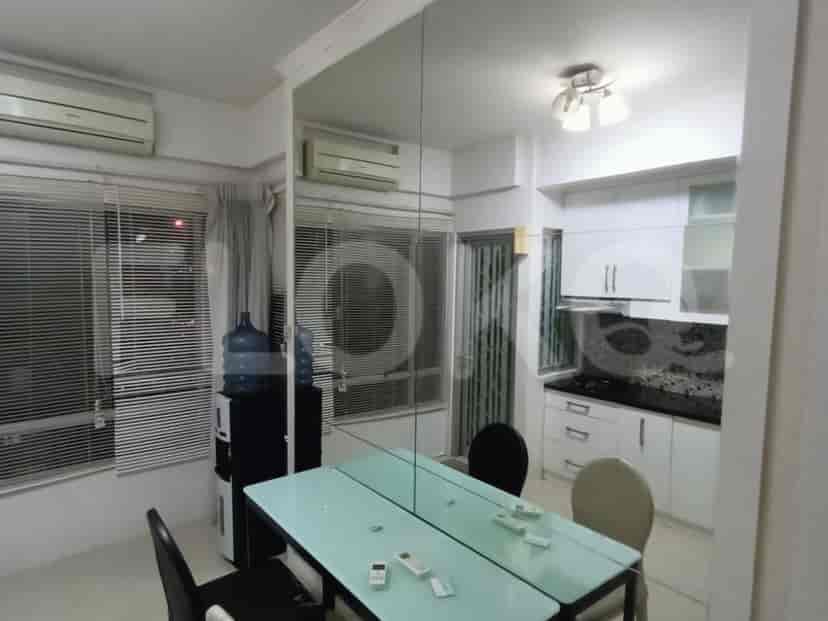 A dining area with a mirrored wall and a small, modern kitchen.