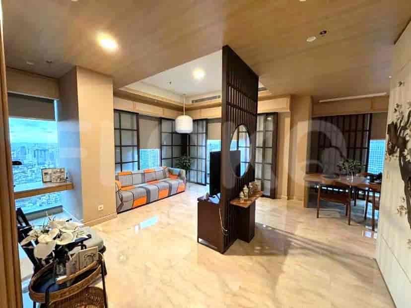 Ruang tamu yang luas dengan sofa berpola, pembatas kayu dengan TV, dan area makan dengan pemandangan kota.