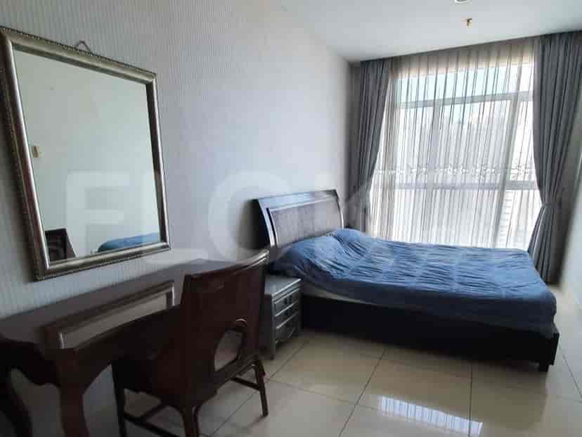 A bedroom with a double bed, desk, mirror, and window.