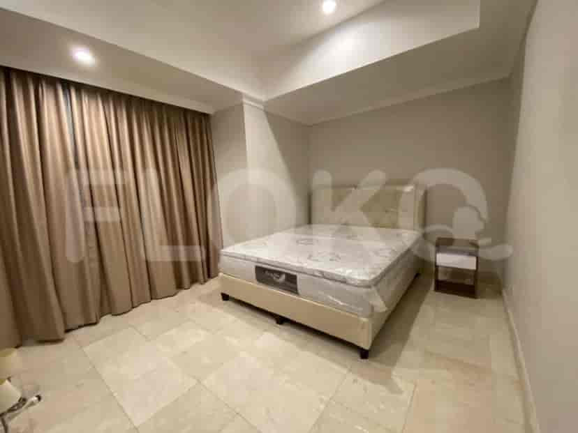 Another bedroom featuring a bed with a beige headboard, bedside table and large windows with curtains.