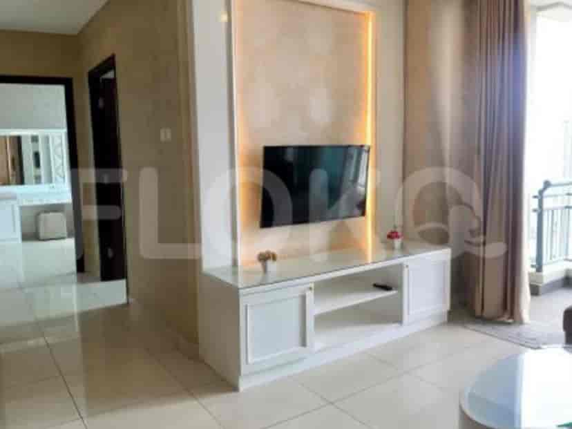 Ruang tamu modern dengan unit hiburan built-in, TV, dan jendela besar.