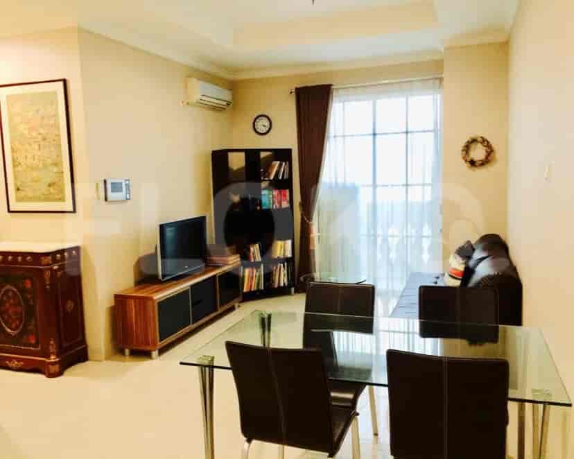 Living room with a glass dining table, a dark sofa, and a wooden TV stand.