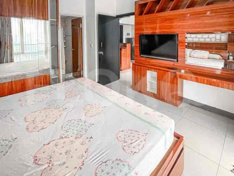 Kamar tidur modern yang menampilkan tempat tidur, TV yang dipasang di dinding, dan pintu lemari cermin.