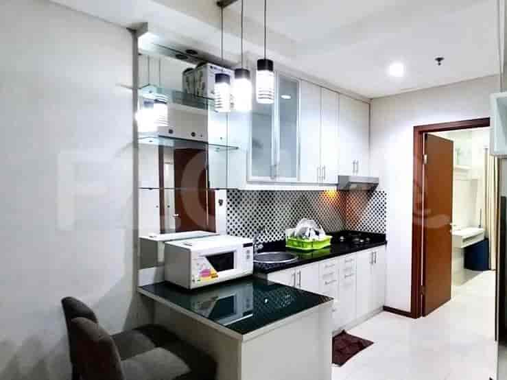 A well-lit kitchen with white cabinets, a black countertop, and a built-in microwave.