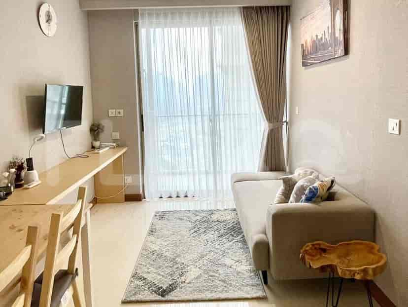 Living area with a desk, TV, and sofa near the window.