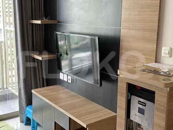 A living room with a mounted TV and wooden cabinets, with a touch of blue.