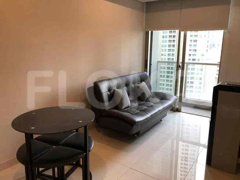 A living room with a dark sofa, round table, and access to a balcony.