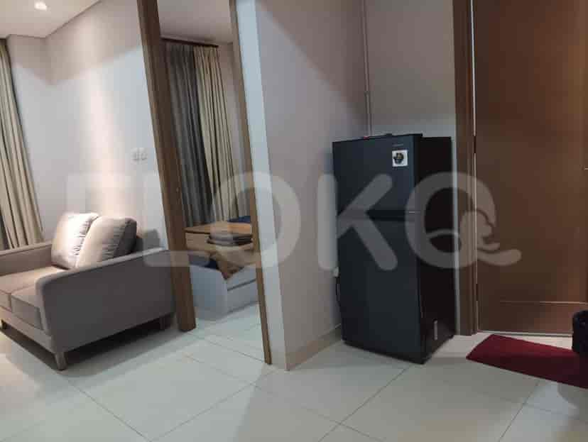 A view of a bedroom and a refrigerator in a small apartment.