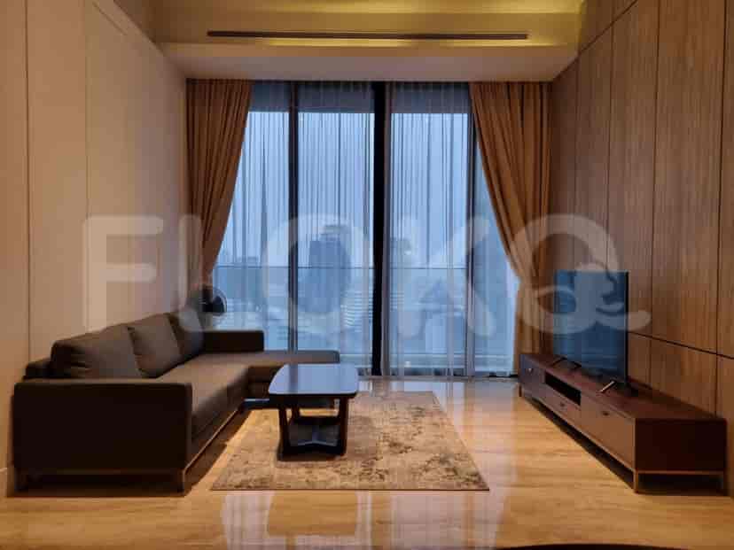 Modern living room with a grey L-shaped sofa, smart TV, and large windows offering a city view.