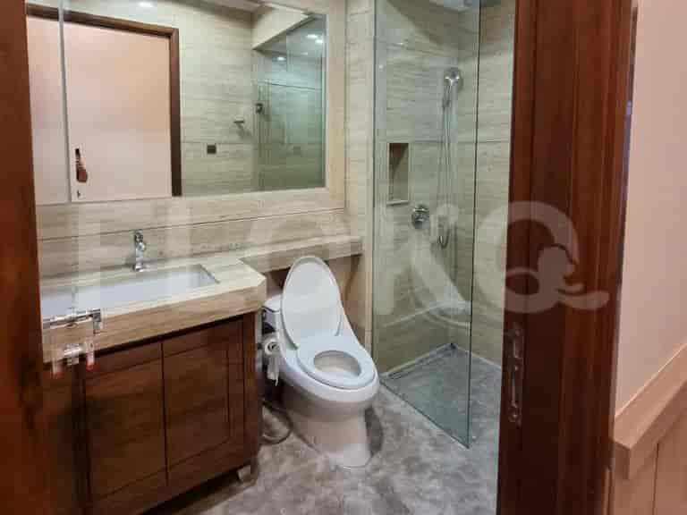 Kamar mandi modern dengan meja rias, toilet, dan pancuran kaca.