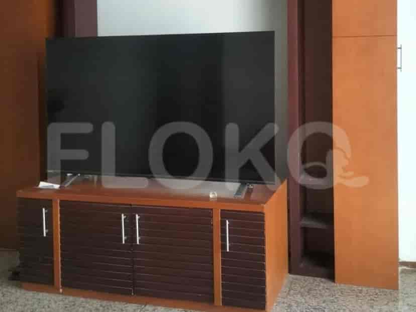 Entertainment setup with a large TV on a brown cabinet.