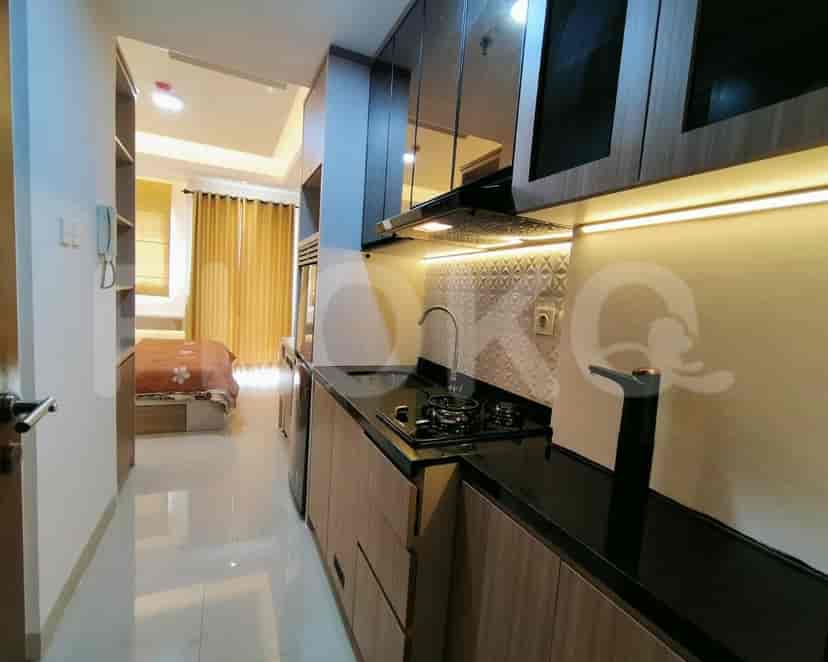 A modern kitchen with wooden cabinets, a black countertop, and overhead lighting.