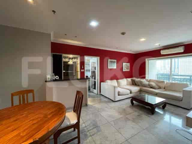 A dining area with a wooden table and chairs is next to a living room with a white sofa and city views.