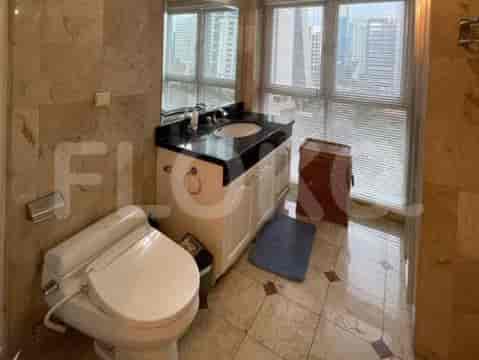 A spacious bathroom featuring a vanity, toilet, and a large window overlooking the city.