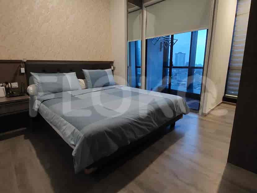 A bedroom with a large bed, wooden flooring, and a view of the city.